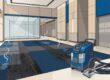 A commercial carpet cleaning machine in an office lobby with stained flooring.